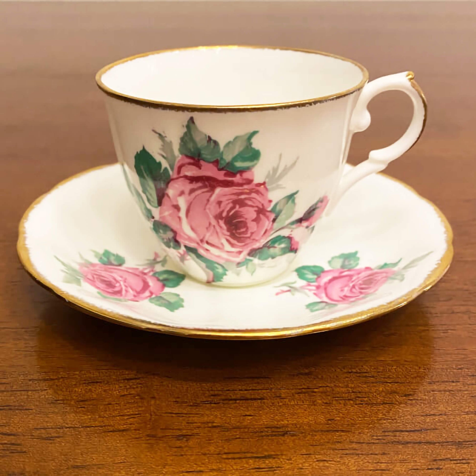 Jason-bone-china-collectible-teacup-and-saucer-set,-#J554,-featuring-pink-roses-and-green-leaves,-accented-by-gilt-trim-on-the-edge-of-the-cup-and-saucer.-Excellent-condition.-Makes-a-great-gift.-Shop-eBargainsAndDeals.com.